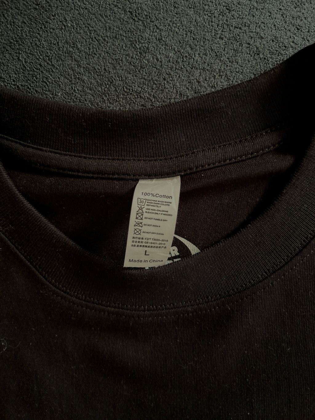 Close-up of a black hoodie with a tag on a gray surface